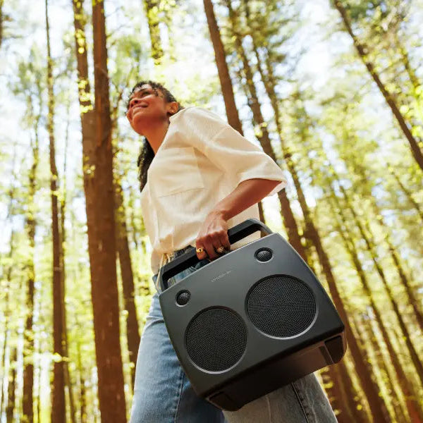 Person holding a portable speaker in a forest
